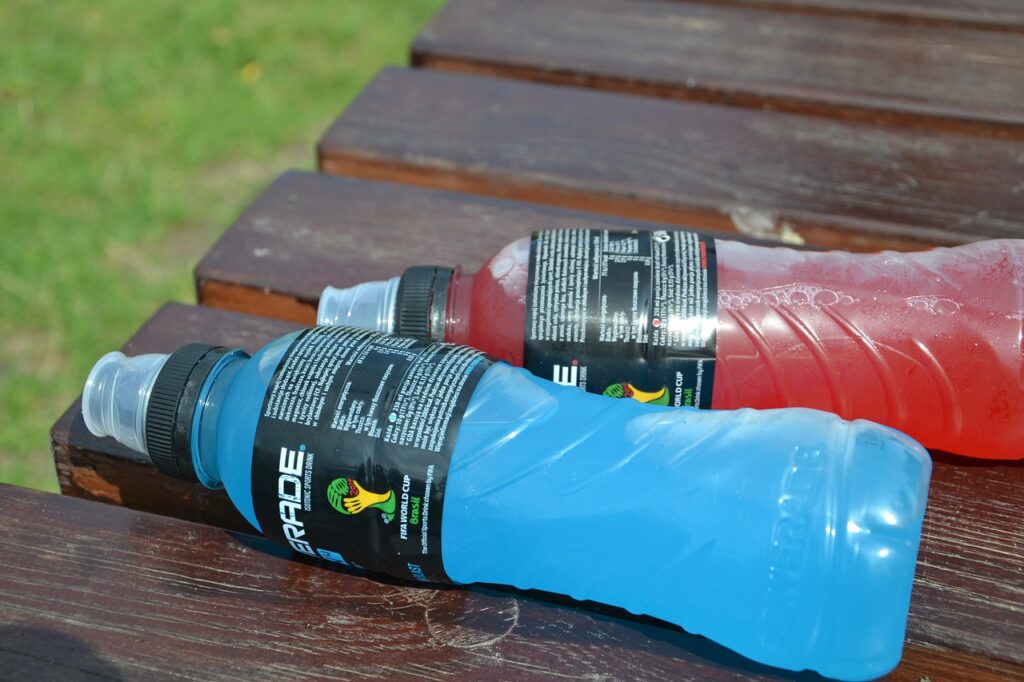 Zwei Sportgetränke in Plastikflaschen auf einer Holzbank